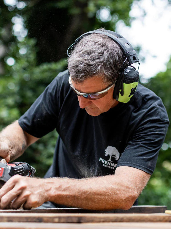 Vakman met bluetooth-gehoorbescherming aan het werk aan een machine